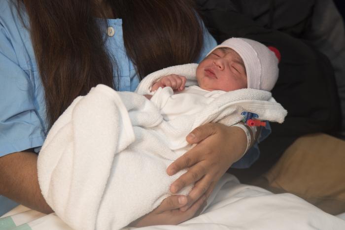 Los padres del primer bebé oscense posan con el pequeño.