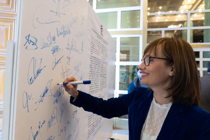 María Antoñanzas firma en el mural del manifiesto.
