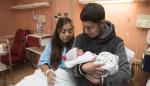 Los padres del primer bebé oscense posan con el pequeño.