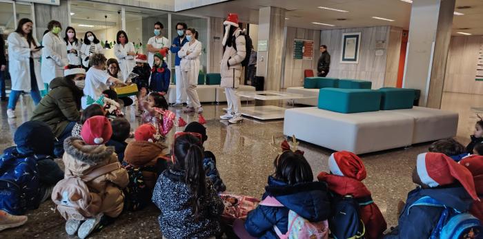 Alumnado del Colegio San José de Calasanz durante la entrega de adornos navideños en el hall del Hospital de Barbastro.