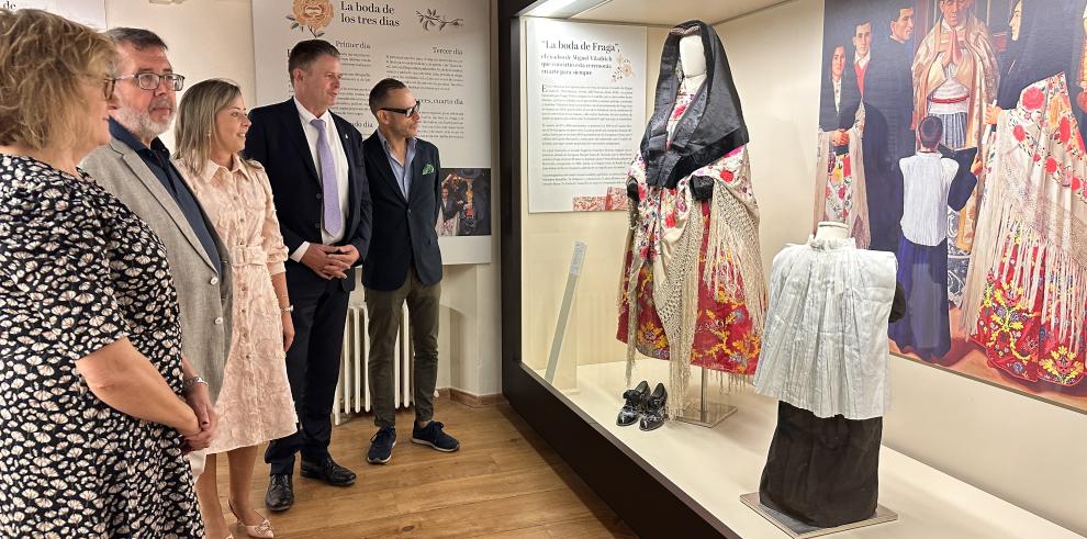 La comisaria de la exposición, el director del Museo de Zaragoza, la concejal de Cultura de Fraga, el alcalde de Fraga y el director general de Cultura contemplan la vitrina dedicada a la indumentaria tradicional en la boda.